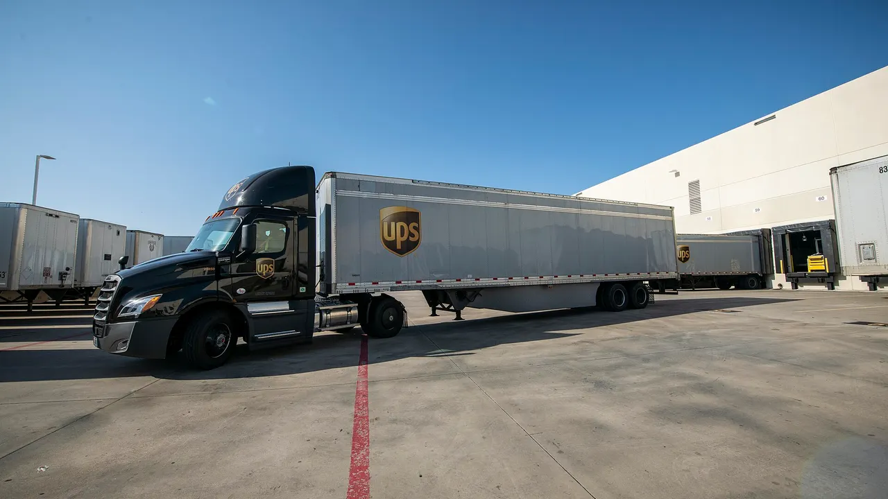 A UPS semi-trailer truck backing up to an offload dock at a facility in Arlington, Texas